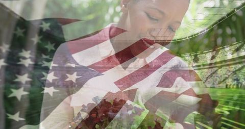 Patriotic woman holding bouquet in double exposure with stadium and green foliage