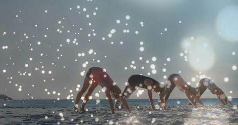 Sunrise beach yoga flow with four women holding downward dog and dreamy bokeh lights