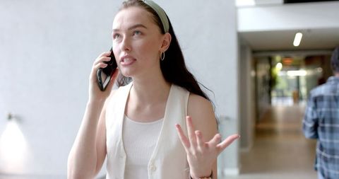 Young Professional Gesturing During Phone Call in Office Corridor