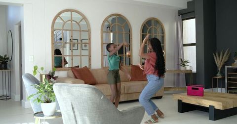 African mother and daughter dancing with golden ball in bright contemporary living room