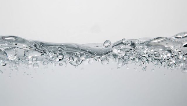 Crystal clear water wave crest with suspended bubbles and droplets, minimal background