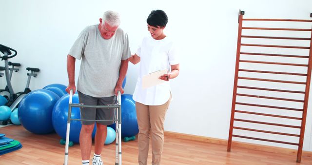 Elderly man is using a walker for assistance during a physiotherapy session, with a therapist providing help and encouragement. This scene highlights themes of recovery, rehabilitation, and senior care. Ideal for health care articles, rehabilitation center promotions, or educational materials on geriatrics.