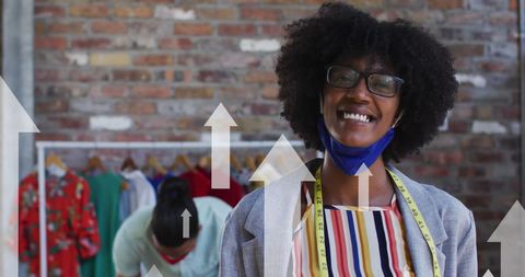 charming scene featuring a fashion designer smiling with a face mask amid pandemic challenges, surrounded by stylish garments on a rack. digital arrows convey the concept of business growth and global connectivity despite covid-19 challenges. ideal for use in articles or presentations focused on innovation in the fashion industry, business resilience, design, and digital transformation during challenging times.