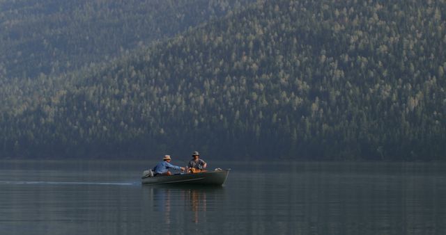 Two men fishing on peaceful mountain lake during sunset. Perfect for nature, relaxation, and outdoor activity themes in marketing, travel promotions, and inspirational content.