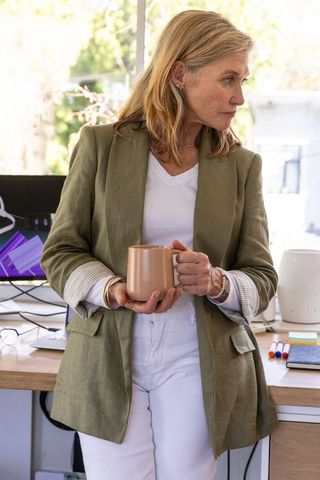 Middle-Aged Woman Reflecting at Modern Office Desk with Coffee Mug