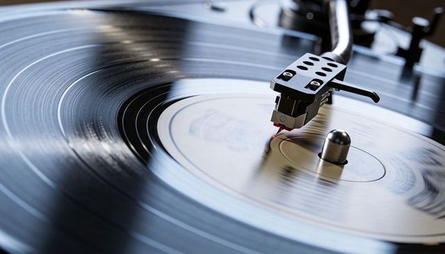 Spinning vinyl lp turntable stylus tracking grooves close-up with reflective highlights