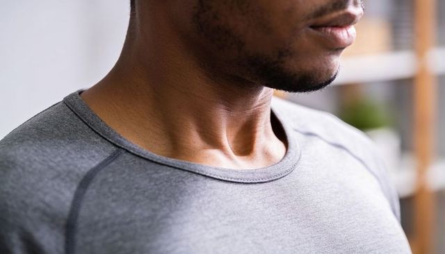 Male wearing heather grey crewneck showing short stubble and minimalist interior closeup