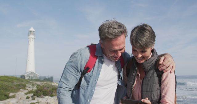 Senior Couple Exploring Beach with Tablet by Lighthouse - Download Free Stock Images Pikwizard.com