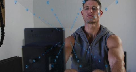 Male Athlete Monitoring Performance on Rowing Machine with Blue Data Overlay
