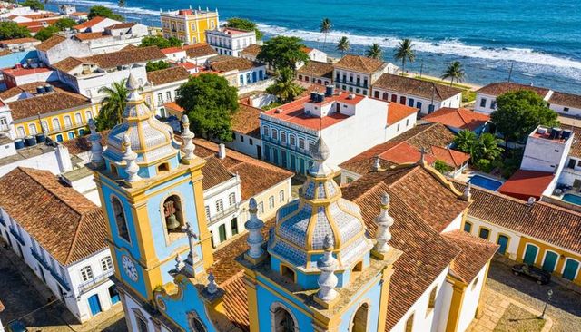 Baroque colonial church twin towers overlooking coastal town with colorful facades