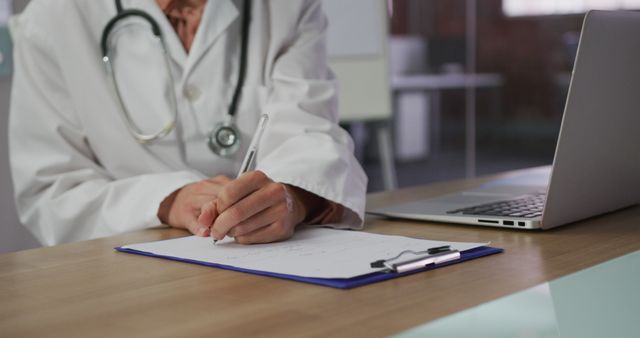 Doctor Writing Notes at Desk with Laptop - Download Free Stock Images Pikwizard.com