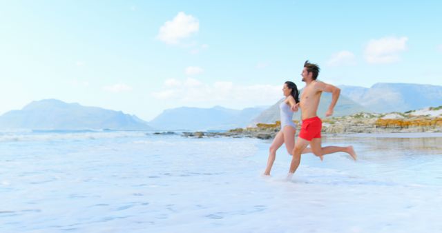 Happy caucasian couple holding hands and running on beach, copy space. Relationship, togetherness, summer, leisure, vacation and lifestyle, unaltered.