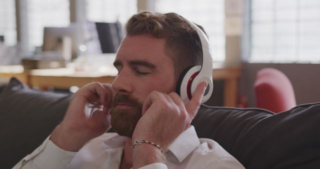 Bearded man enjoying music with headphones on couch - Download Free Stock Images Pikwizard.com