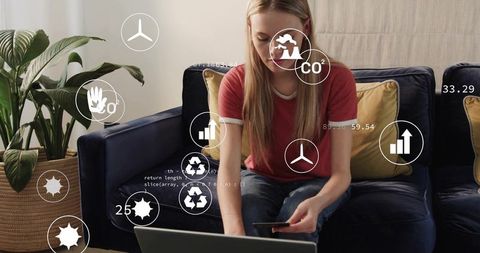 Young woman analyzing sustainable energy and eco analytics on laptop from couch