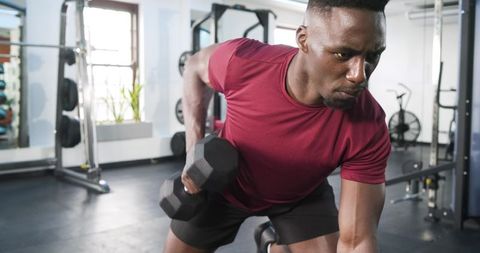 Man Performing Dumbbell Row in Modern Gym Intensively Training