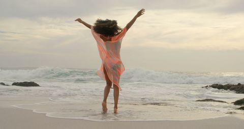 Joyful Woman Dancing by Ocean on Tranquil Beach