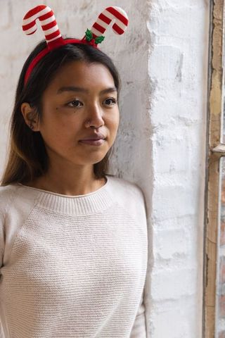 Contemplative woman in cozy sweater with candy cane headband