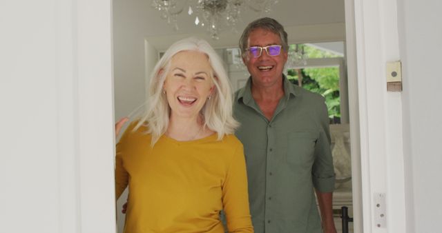 Image of happy caucasian senior couple opening doors and welcoming friends. retirement lifestyle, spending quality time with friends.