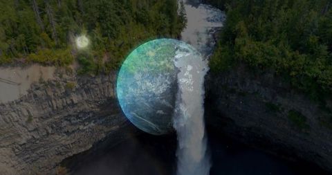 Plunging waterfall into dark gorge with ethereal blue orb overlay, forest canyon