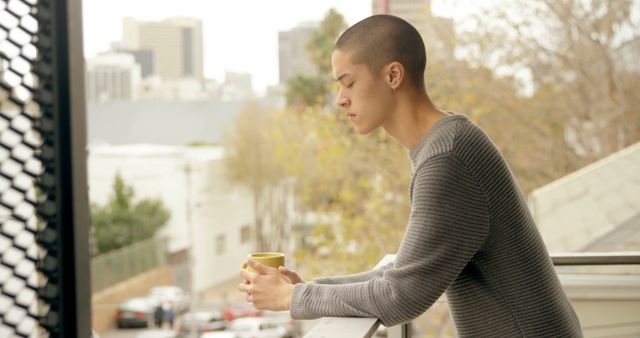 Pensive Young Multiracial Woman with Shaved Head Holding Mug on Balcony - Download Free Stock Images Pikwizard.com