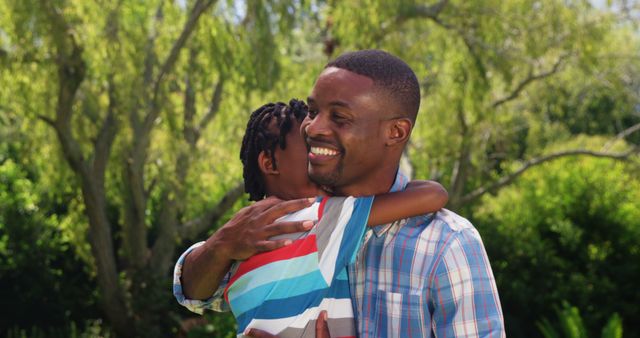Father embracing young son with big smile in a sunny park, underlining strong family bond and happiness. Represents love, care, and joy between parent and child. Ideal for family and lifestyle blogs, parenting articles, and advertisements promoting outdoor activities or family products.