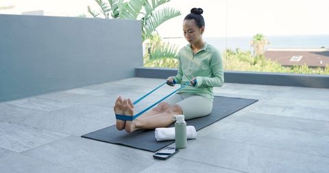 Woman stretching with resistance band on outdoor terrace