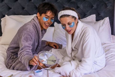 Couple enjoying skincare night applying blue under-eye patches while wearing plush robes