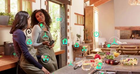 Two women prepping vegetables in sunlit farmhouse kitchen with eco energy icons overlay