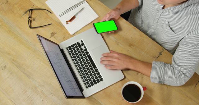 Person Working on Laptop While Holding Smartphone with Green Screen - Download Free Stock Images Pikwizard.com