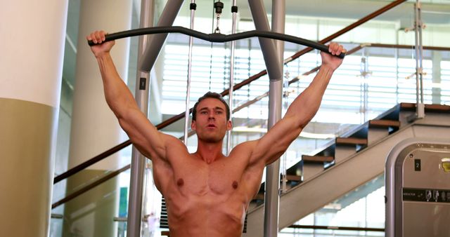 Muscular man performing overhead pull-down exercise at gym - Download Free Stock Images Pikwizard.com