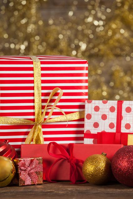 Close-up view of beautifully wrapped Christmas gifts and festive baubles on a wooden table. Ideal for holiday greeting cards, festive advertisements, and seasonal blog posts. Perfect for conveying the warmth and joy of the Christmas season.