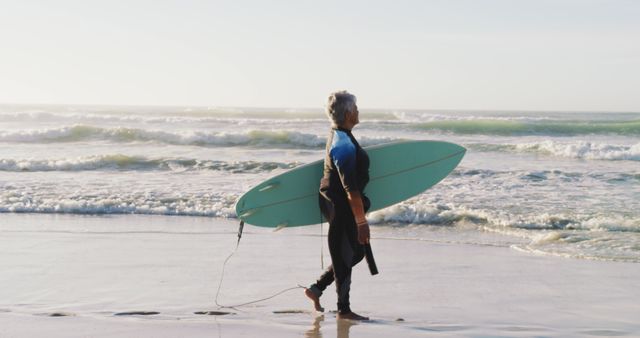 Ideal for articles on senior fitness, active retirement, beach lifestyles. Perfect for use in advertisements promoting surfing gear for older adults or healthy aging programs.