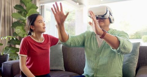 Father Wearing VR Headset Bonding with Curious Daughter in Modern Living Room