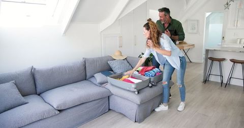 Couple Packing Suitcase for Vacation in Comfortable Living Room