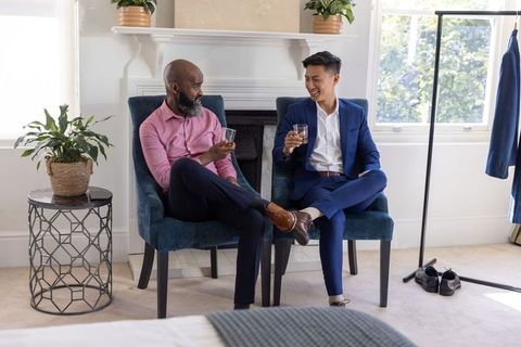 Business colleagues sharing drinks and conversation in modern suite with fireplace