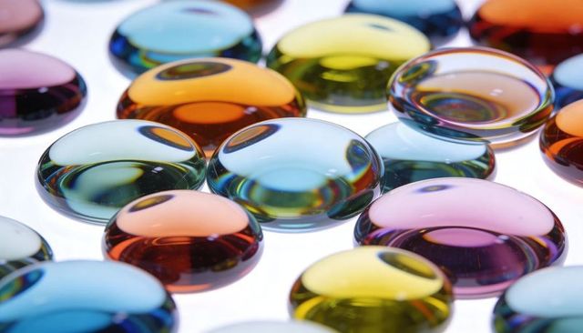 Glowing multicolor glass pebbles showing iridescent refraction on white backlight