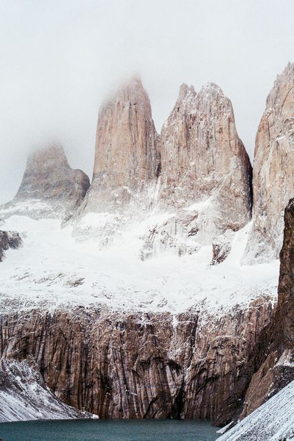 Snow-covered mountain peaks in Torres del Paine National Park, Chilean Patagonia. The icy rock formations and serene environment illustrate the beauty of the untouched wilderness. Ideal for travel advertisements, nature documentaries, adventure tourism, and environmental conservation campaigns.