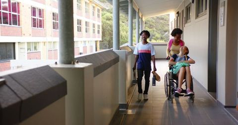 Diverse kids navigating school corridor with wheelchair