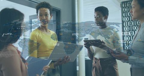 Collaborating women in office analyzing global data on tablets with digital map overlays