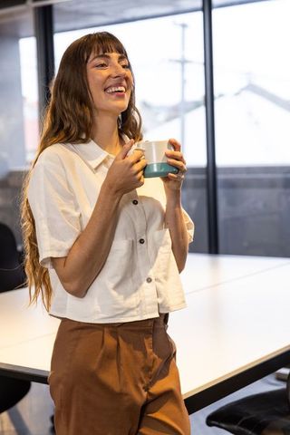 Professional woman enjoying coffee break in minimalist office