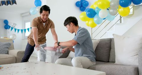 Two Men Collaborating on Post-Party Cleanup in Living Room