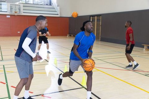 Young black men practicing basketball drills in indoor gym cones for agility and teamwork