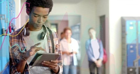 Asian teen tapping tablet in school hallway wearing headphones and plaid shirt