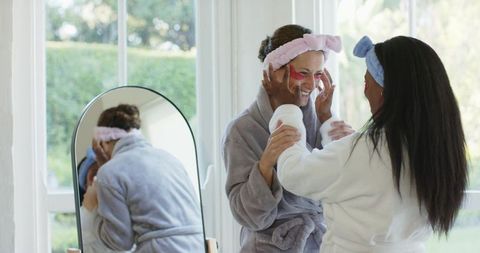 Diverse friends enjoying skincare routine in cozy bathrobes
