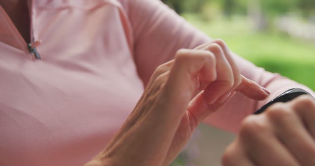 This image depicts a person interacting with a smartwatch outdoors, providing a tech-centric look at modern fitness routines. Ideal for use in health and wellness blogs, technology websites, and advertisements for smart devices.