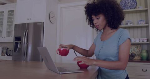 African American Woman Working at Kitchen Island with Mugs and Laptop