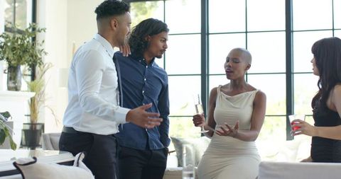 Diverse professionals networking and socializing with drinks in sunlit modern living room