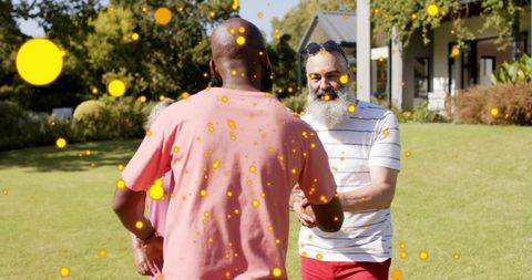 Two men greeting and shaking hands on sunny suburban front yard with playful bokeh overlay