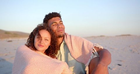 Biracial Couple Enjoying Calm Beach Sunset Wrapped in Blanket