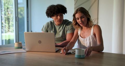 Young couple collaborating at home office with laptop